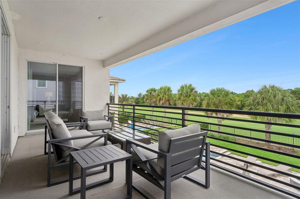 A balcony with outdoor furniture overlooks a golf course and a swimming pool — 972 JACK NICKLAUS CT, REUNION, FL