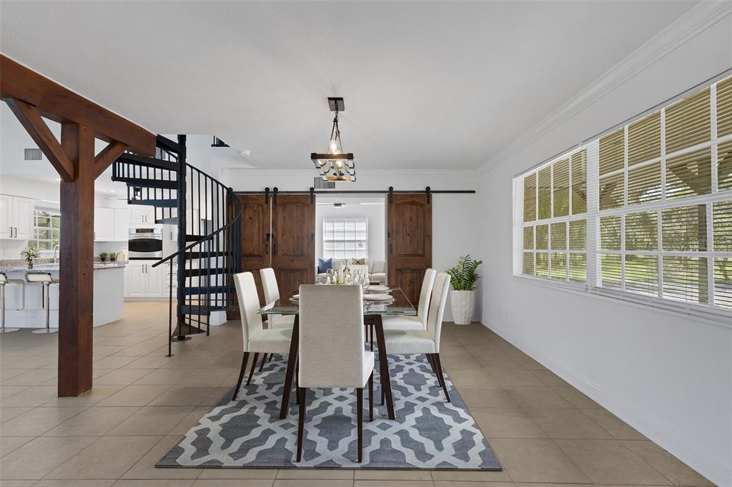 A dining room with a glass table, spiral staircase, and wooden barn doors — 28706 102ND DRIVE E, MYAKKA CITY, FL