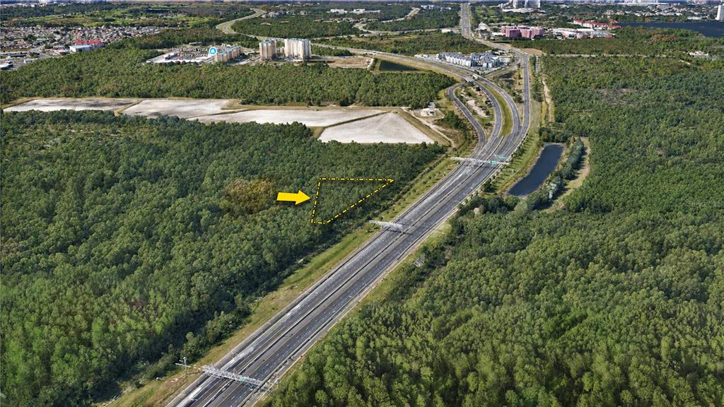 An aerial view shows a triangular plot of land outlined in yellow next to a highway — Vacant Land on S APOPKA VINELAND ROAD, ORLANDO, FL