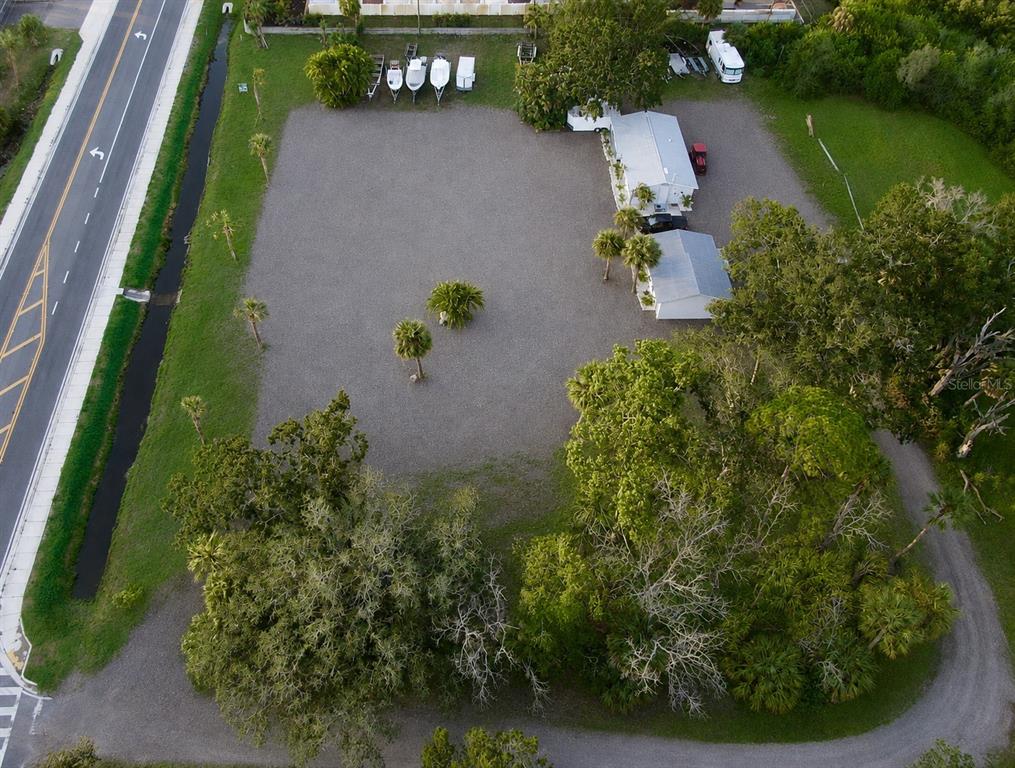 An aerial view shows a gravel lot with two small buildings and several parked boats — 1322 N PINELLAS AVENUE, TARPON SPRINGS, FL
