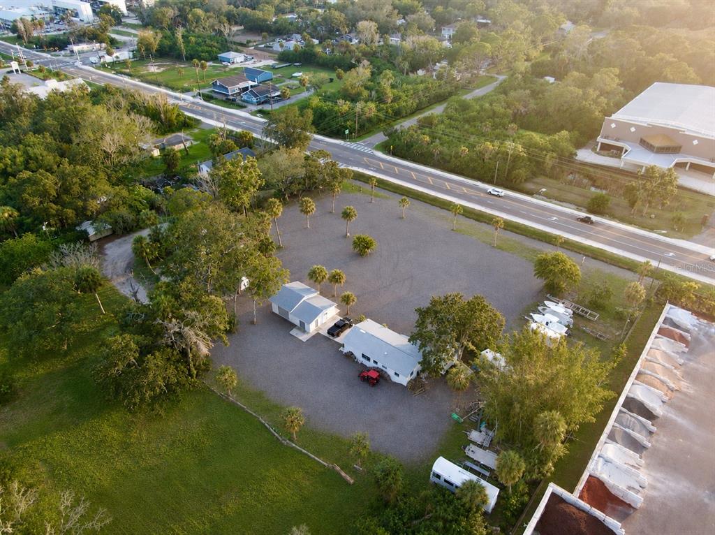 A gravel driveway leads toward a Kora Motorsports sign and trees on a sunny day — 1322 N PINELLAS AVENUE, TARPON SPRINGS, FL