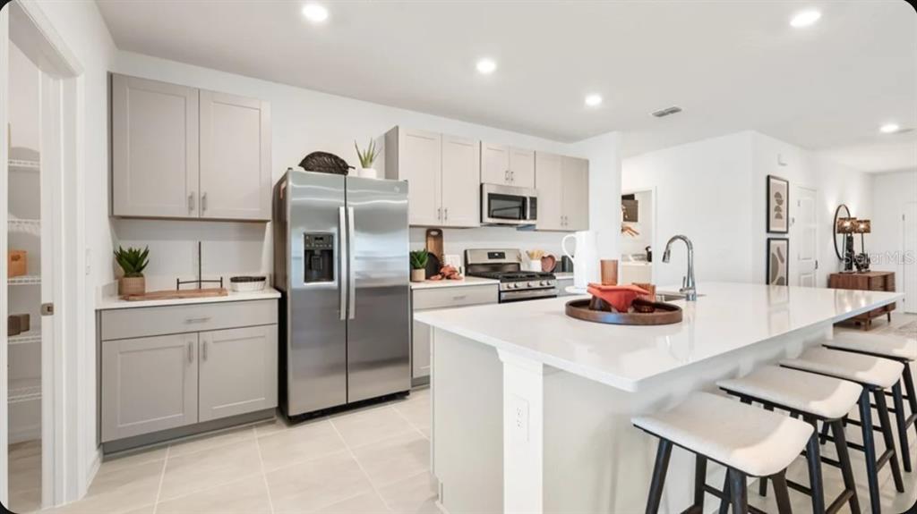 A kitchen with light gray cabinets, stainless steel appliances, and a large white island — 13321 COMMONS AVENUE, PARRISH, FL