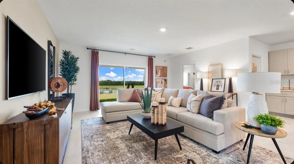 A living room features a sectional sofa, a coffee table, and a view of a pond — 13321 COMMONS AVENUE, PARRISH, FL