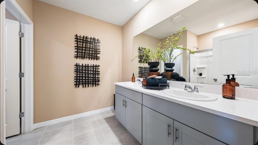 A bathroom features a double vanity with grey cabinets, white countertops, and beige walls — 13321 COMMONS AVENUE, PARRISH, FL
