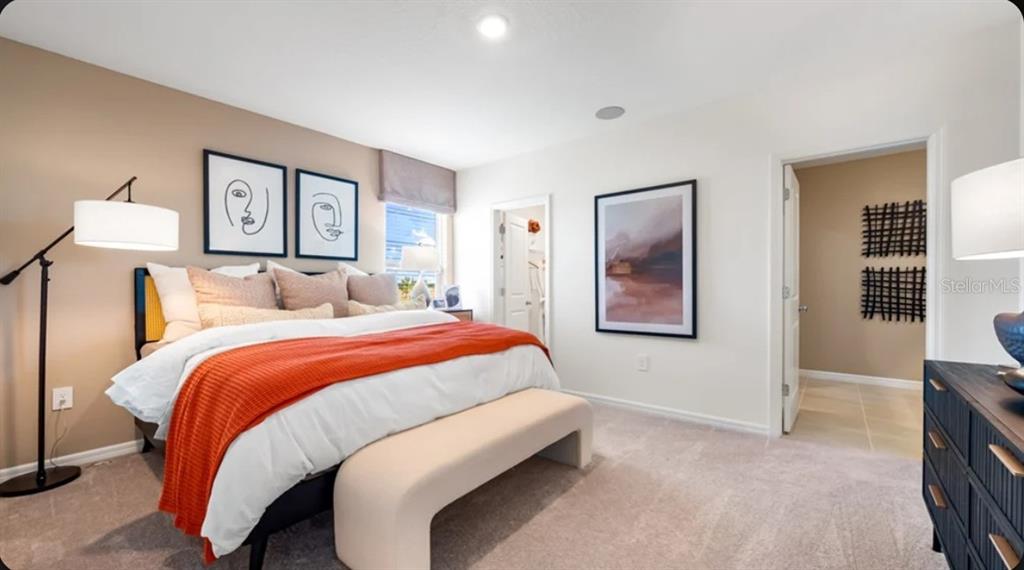 A bedroom features a bed with an orange throw, a bench, and framed wall art — 13321 COMMONS AVENUE, PARRISH, FL