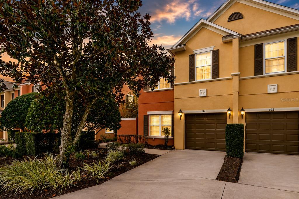 The exterior of a multi-story tan townhouse features a ground-level patio and a second-floor balcony — 894 ASSEMBLY COURT, REUNION, FL