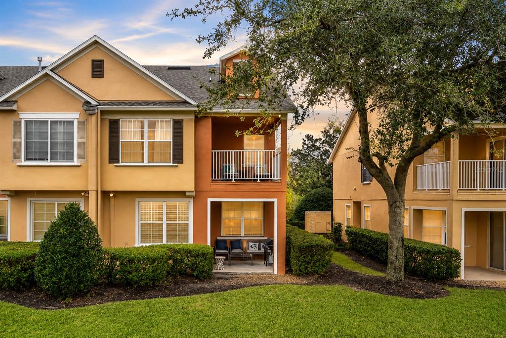 An exterior view of orange apartment buildings situated alongside a golf course fairway and bunker — 894 ASSEMBLY COURT, REUNION, FL