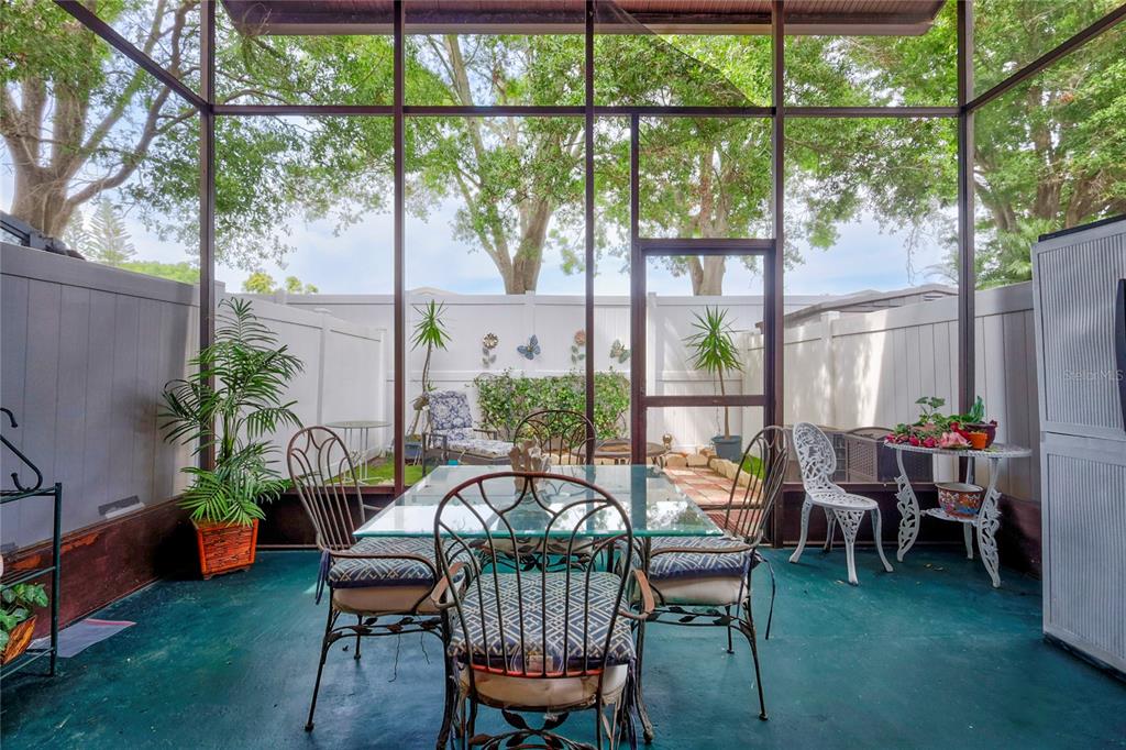 A screened-in patio features a glass dining table, metal chairs, and a green painted floor — 2811 S PINES DRIVE UNIT 15, LARGO, FL