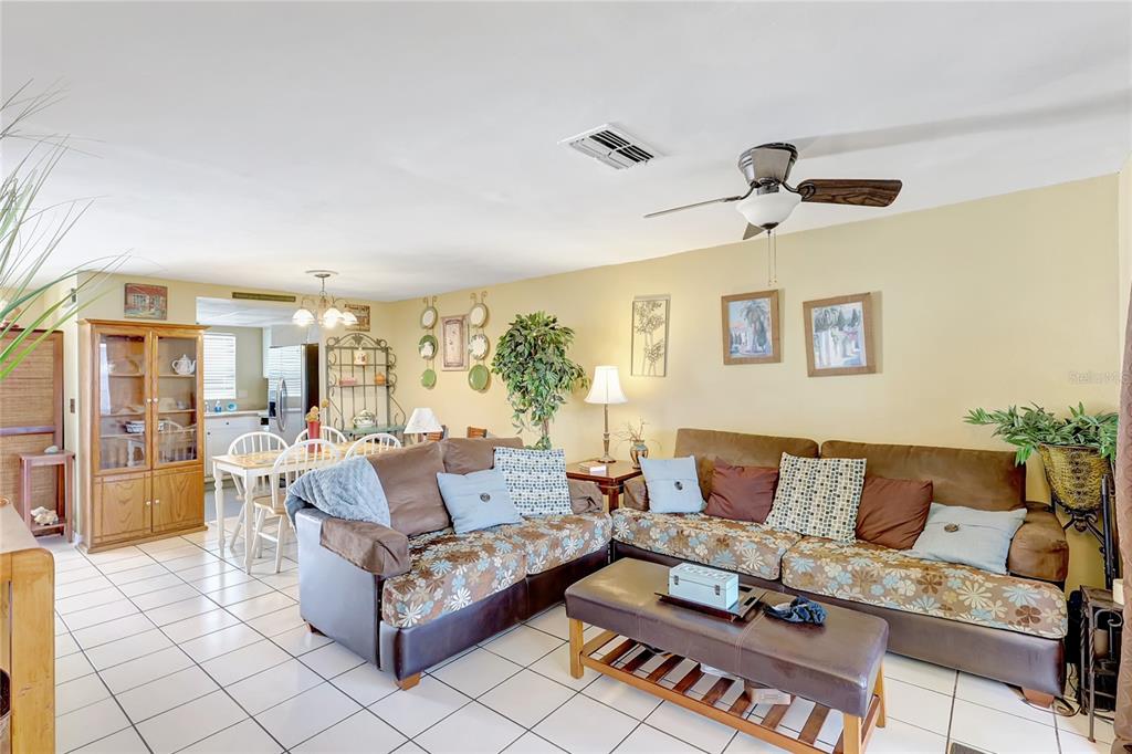 A living room with tile flooring, a brown patterned sofa, and an adjacent dining area — 2811 S PINES DRIVE UNIT 15, LARGO, FL