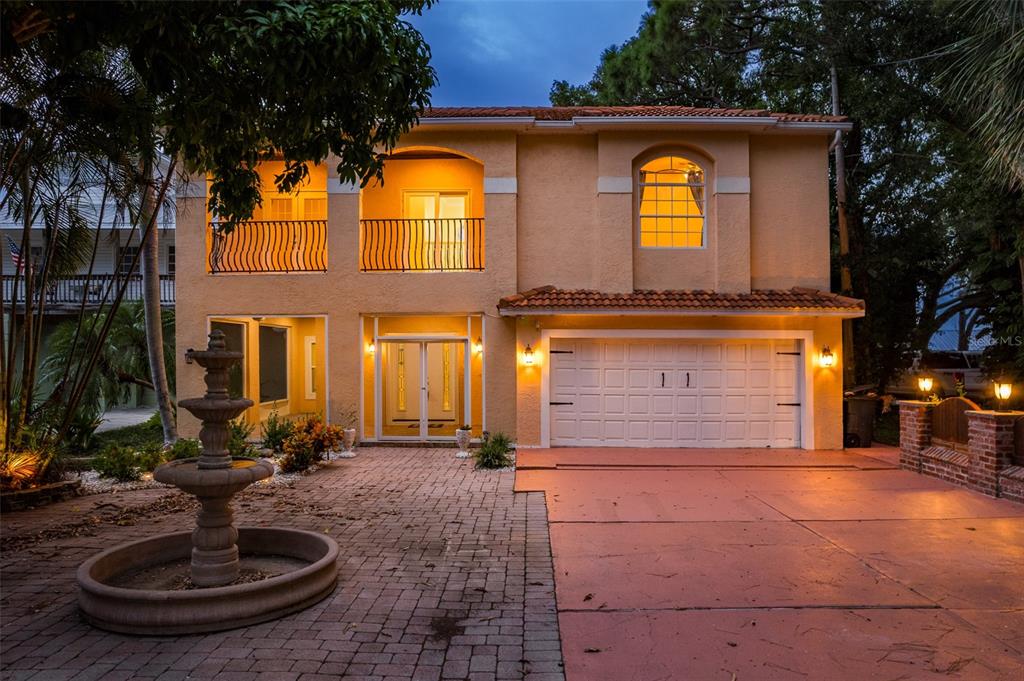 A two-story stucco house with a tiled roof, a fountain, and a two-car garage — 302 SHORE DRIVE, PALM HARBOR, FL