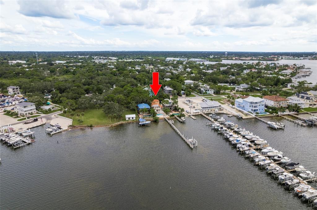 An aerial view shows a waterfront house with a pool and a long boat dock — 302 SHORE DRIVE, PALM HARBOR, FL