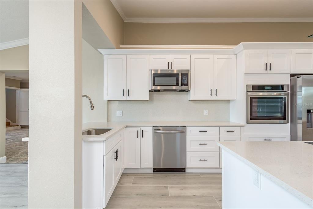 A modern kitchen features white cabinetry, stainless steel appliances, and light-colored countertops — 302 SHORE DRIVE, PALM HARBOR, FL