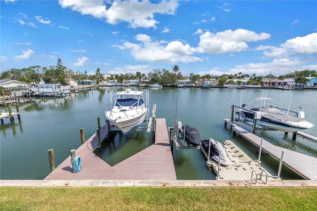 A canal view features two boat lifts with docked vessels and a wooden pier — 100 WINDRUSH BOULEVARD UNIT 1, INDIAN ROCKS BEACH, FL