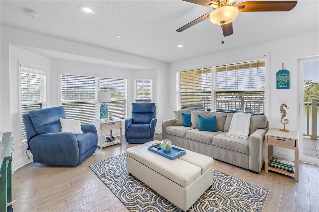 A living room features a beige sofa, two blue recliners, and a white ottoman — 100 WINDRUSH BOULEVARD UNIT 1, INDIAN ROCKS BEACH, FL