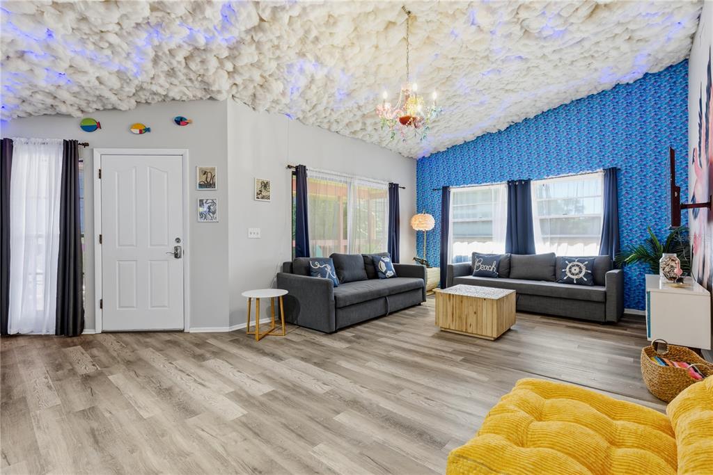 A living room features a cloud-covered ceiling, blue patterned wallpaper, and gray sofas — 527 BEACH ROAD, SARASOTA, FL