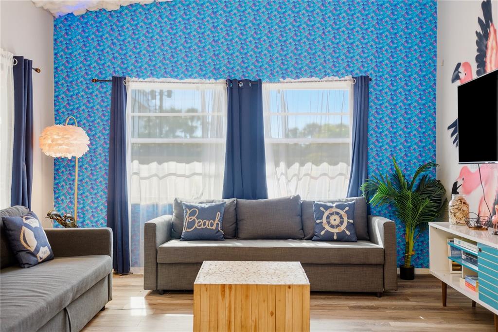 A living room features blue mermaid-scale wallpaper, two gray sofas, and a wooden coffee table — 527 BEACH ROAD, SARASOTA, FL