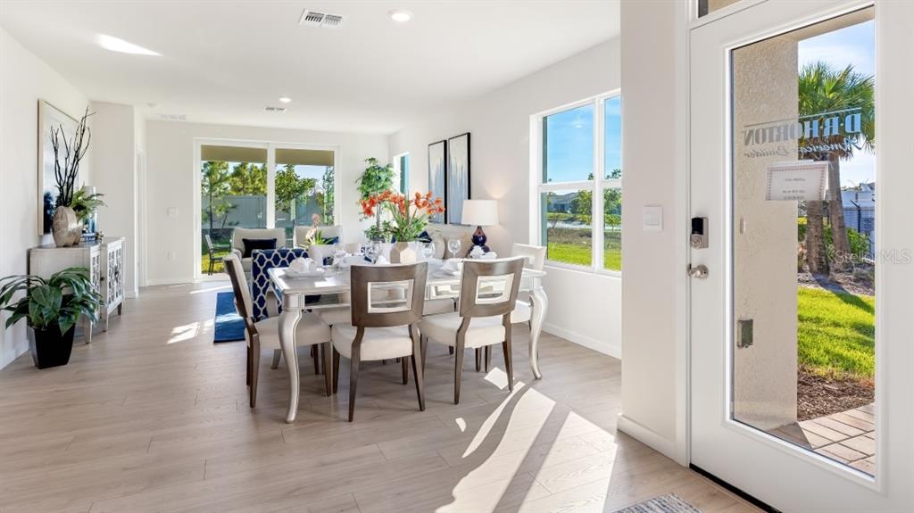 A dining room with a table and chairs sits near a glass door and windows — 4607 SCHUBERT TRAIL, NORTH PORT, FL