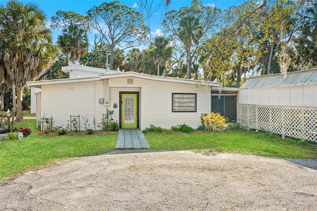 A single-story house with white siding, a lime green front door, and a gravel driveway — 1524 INDIAN BAY ROAD, HERNANDO BEACH, FL
