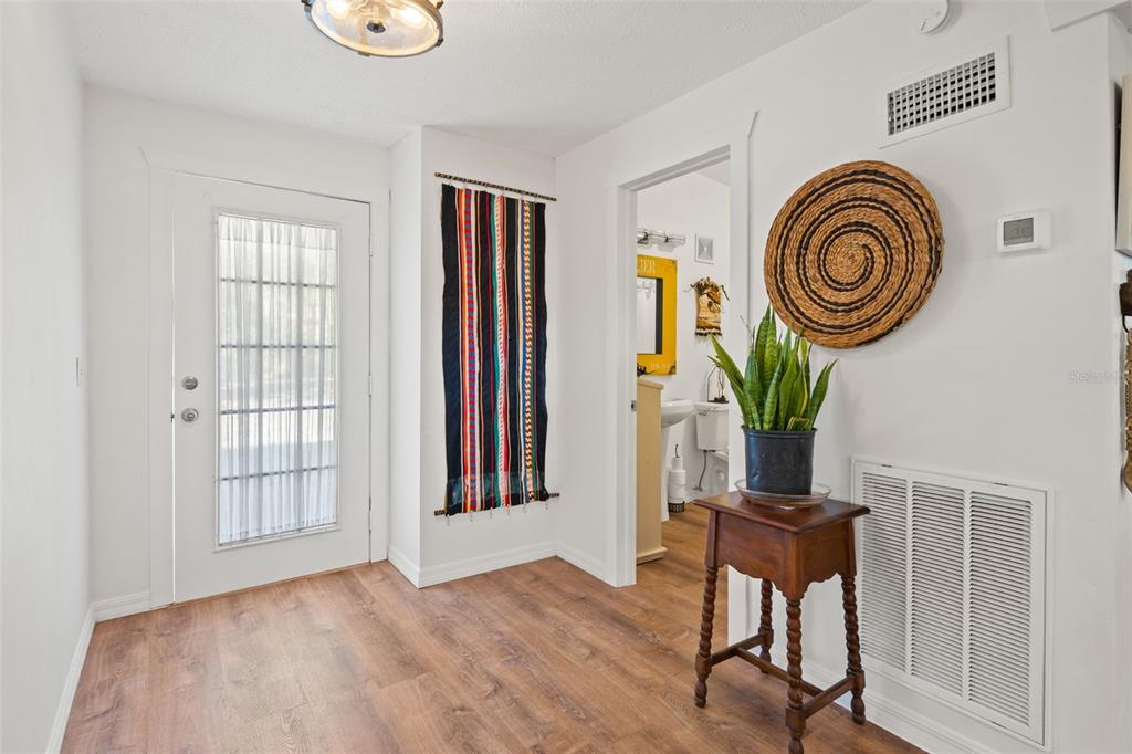 An entryway features wood-look flooring, a white door, a wall hanging, and a small wooden table — 1524 INDIAN BAY ROAD, HERNANDO BEACH, FL