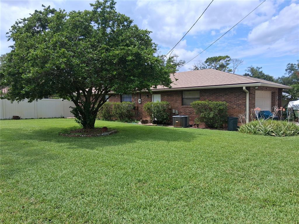 A brick house with a large tree in the front yard under a blue sky — 400 W ORANGE STREET, ALTAMONTE SPRINGS, FL