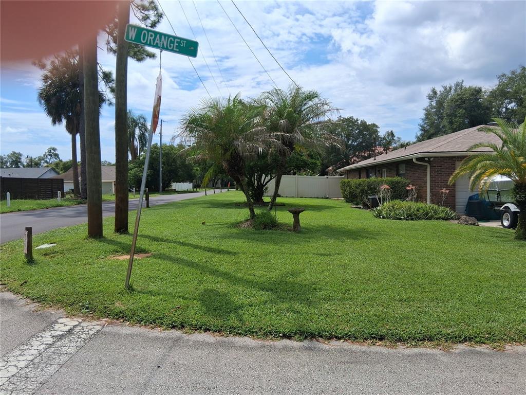 A street sign for W Orange St stands in the grassy front yard of a house — 400 W ORANGE STREET, ALTAMONTE SPRINGS, FL