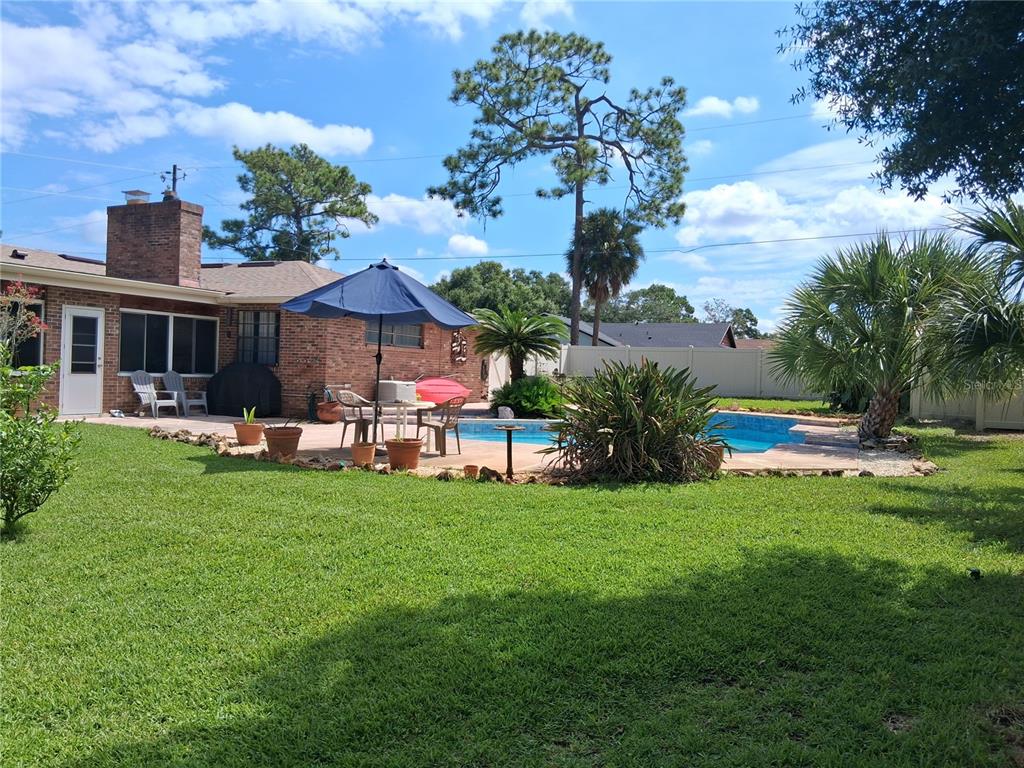 A backyard features a brick house, a swimming pool, a patio, and a blue umbrella — 400 W ORANGE STREET, ALTAMONTE SPRINGS, FL