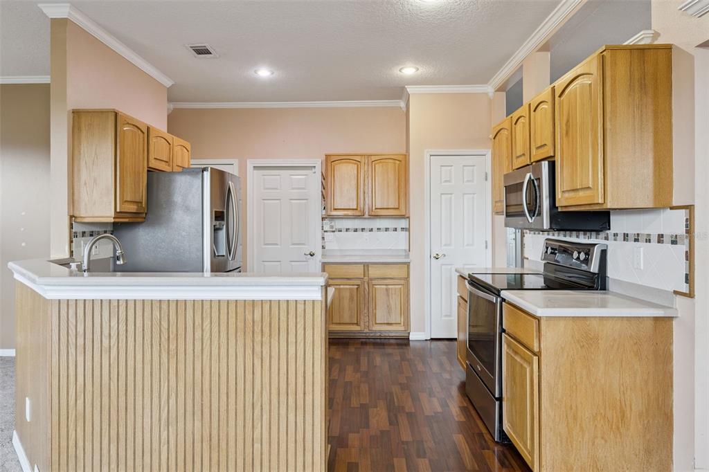 A kitchen features light wood cabinets, stainless steel appliances, and a peninsula with a sink — 15734 THOROUGHBRED LANE, MONTVERDE, FL