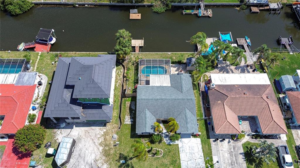 An aerial view shows three houses along a canal with docks, pools, and driveways — 9826 ISLAND HARBOR DRIVE, PORT RICHEY, FL