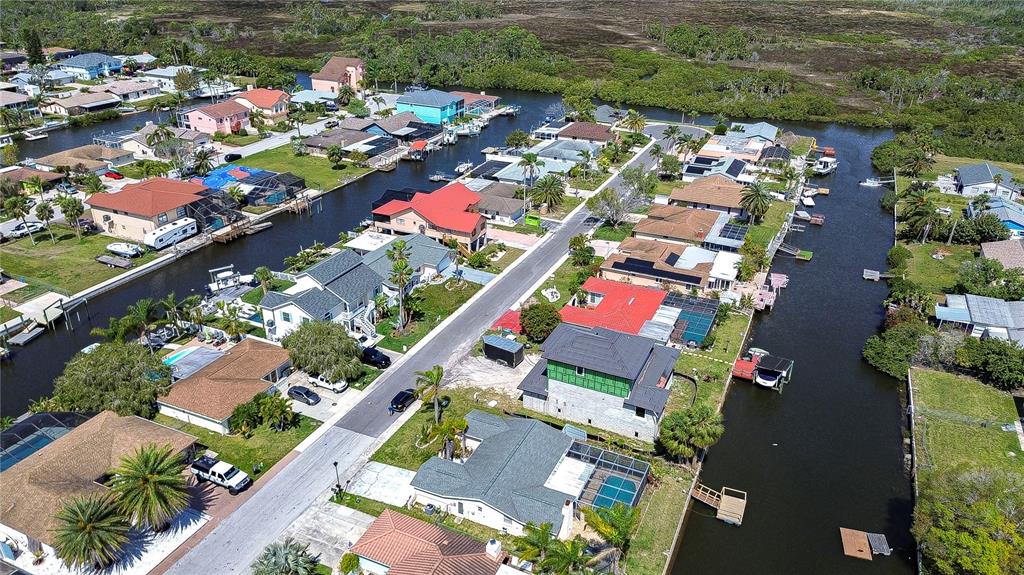 An aerial view shows a residential neighborhood with houses lining two canals — 9826 ISLAND HARBOR DRIVE, PORT RICHEY, FL