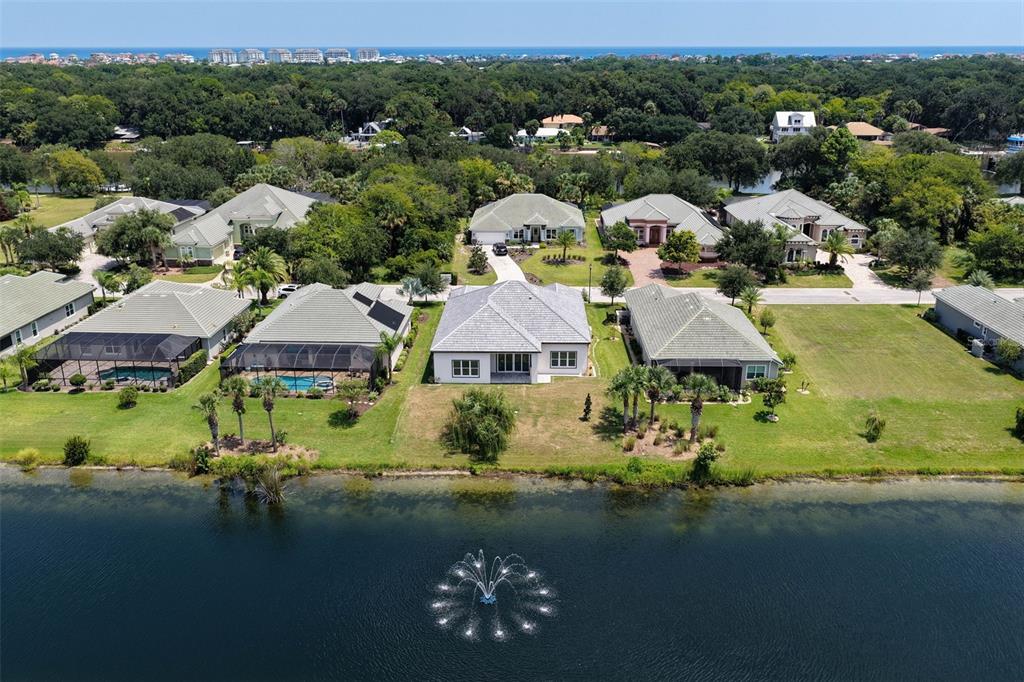 An aerial view shows several suburban houses with tiled roofs situated along a lakefront — 116 LONGVIEW WAY N, PALM COAST, FL