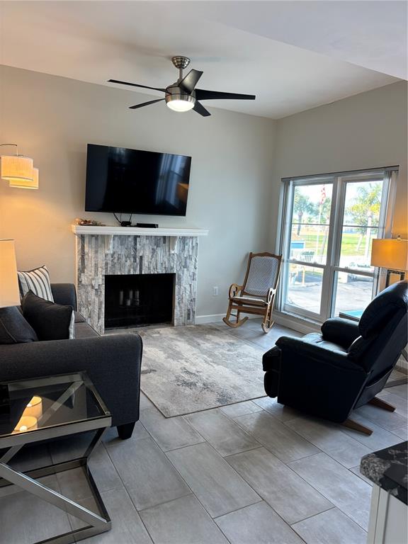 A living room features a stone fireplace, a ceiling fan, and a black recliner — 179 MEDALLION BOULEVARD UNIT E, MADEIRA BEACH, FL