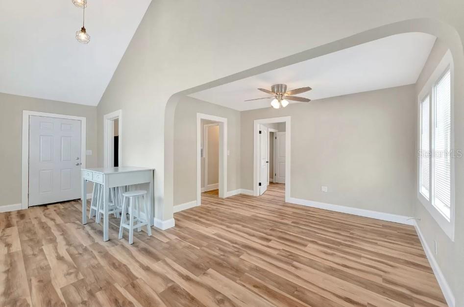 An empty room features light-colored walls, wood-look flooring, an arched entryway, and a ceiling fan — 828 22ND AVENUE N UNIT 1/2, ST PETERSBURG, FL