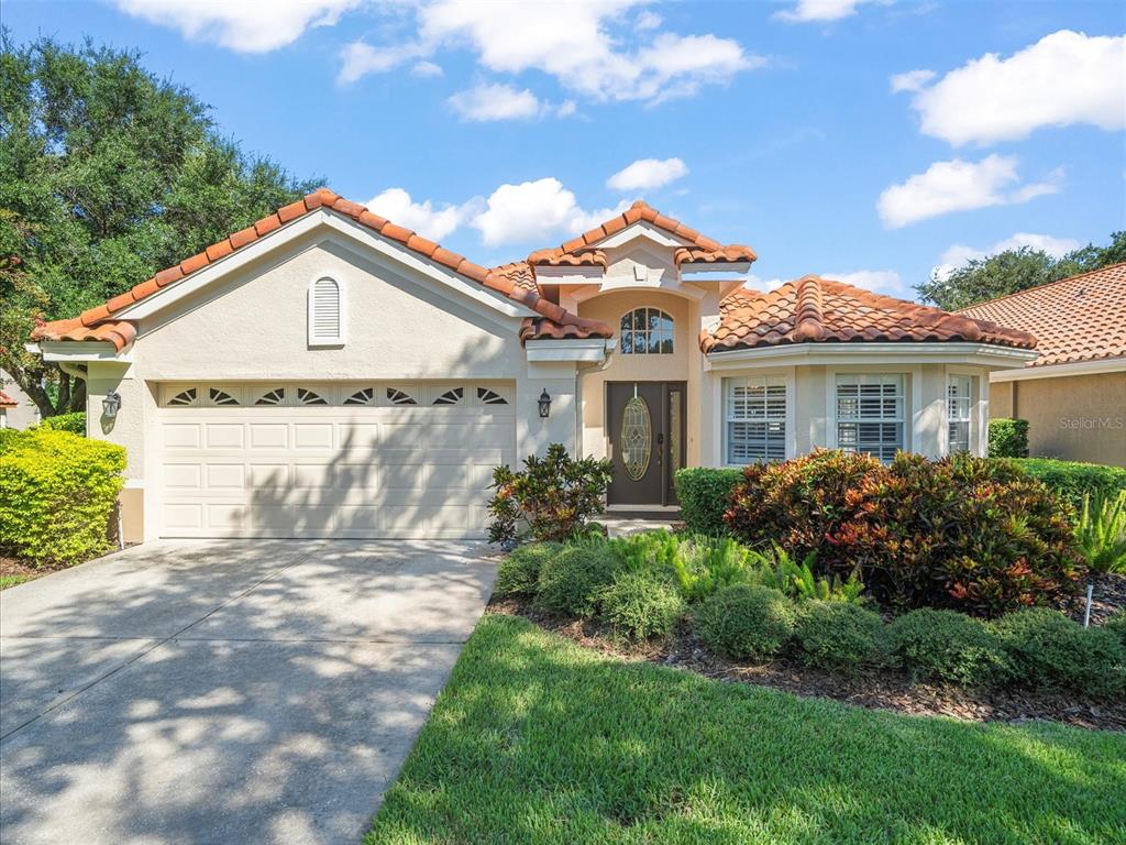 A single-story house with a tile roof, a two-car garage, and a landscaped front yard — 18921 PLACE MARQUETTE, LUTZ, FL