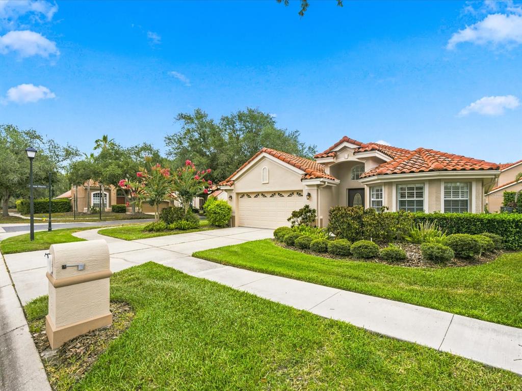 A single-story house with a tile roof, two-car garage, and a manicured front lawn — 18921 PLACE MARQUETTE, LUTZ, FL
