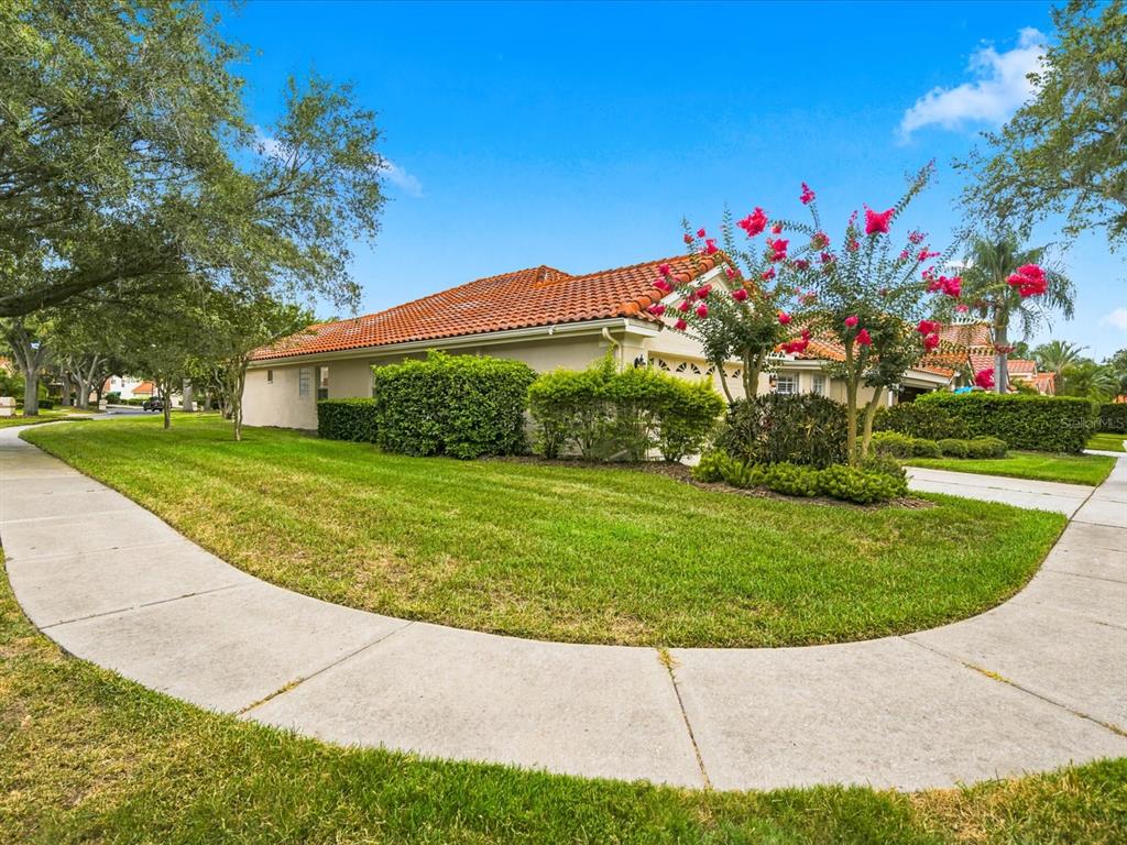 A single-story house with a terracotta tile roof sits behind a curved sidewalk and lawn — 18921 PLACE MARQUETTE, LUTZ, FL