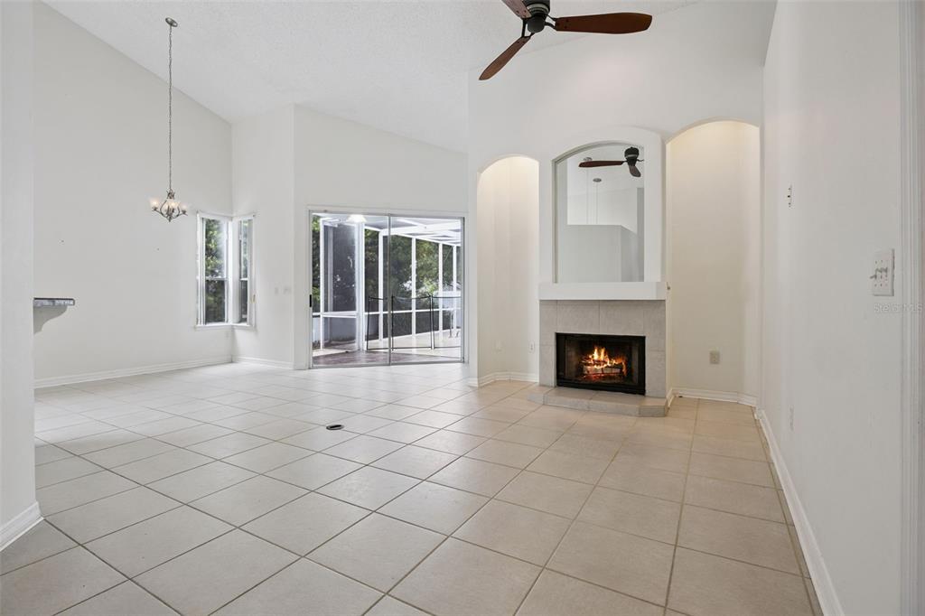 A living room with tile floors, a fireplace, and a sliding door to a screened patio — 3774 HUNTWICKE BLVD, DAVENPORT, FL