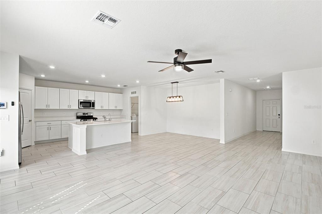 A two-story suburban house with a tan exterior, a two-car garage, and a concrete driveway — 35418 ACKLEY TRACE, ZEPHYRHILLS, FL