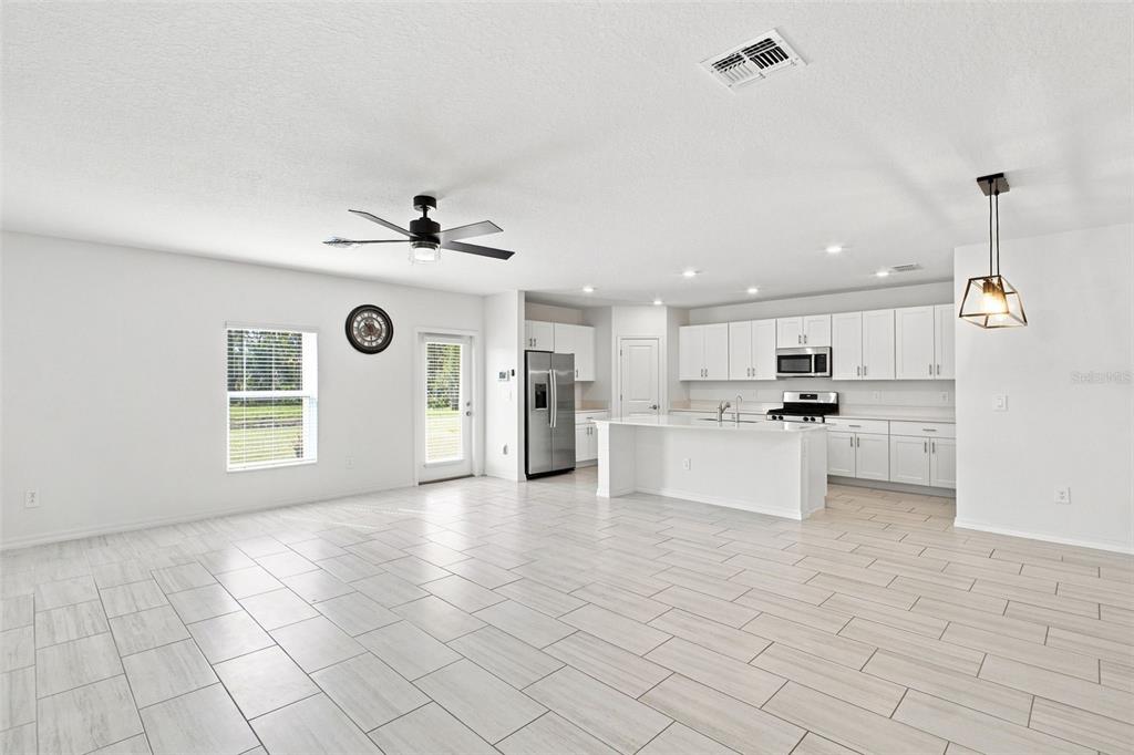 A two-story house with a tan facade, brown garage door, and a small front yard — 35418 ACKLEY TRACE, ZEPHYRHILLS, FL
