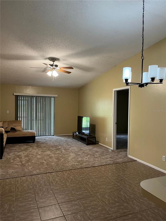 A living room features a ceiling fan, carpeted flooring, a television stand, and sliding glass doors — 39650 US HIGHWAY 19 N UNIT 576, TARPON SPRINGS, FL