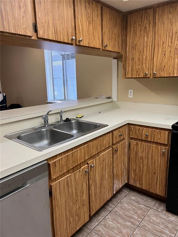 A kitchen features wood-grain cabinets, a stainless steel double sink, and a dishwasher — 39650 US HIGHWAY 19 N UNIT 576, TARPON SPRINGS, FL
