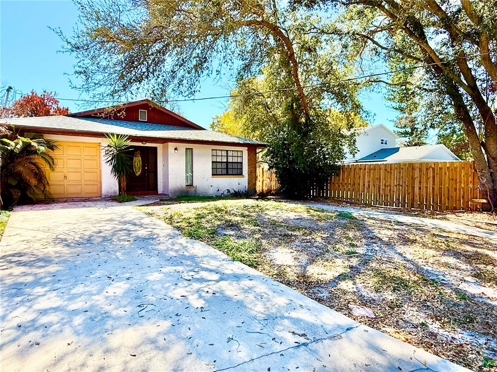A single-story house with a concrete driveway, a garage, and a wooden fence — 8336 JACKSON SPRINGS ROAD, TAMPA, FL