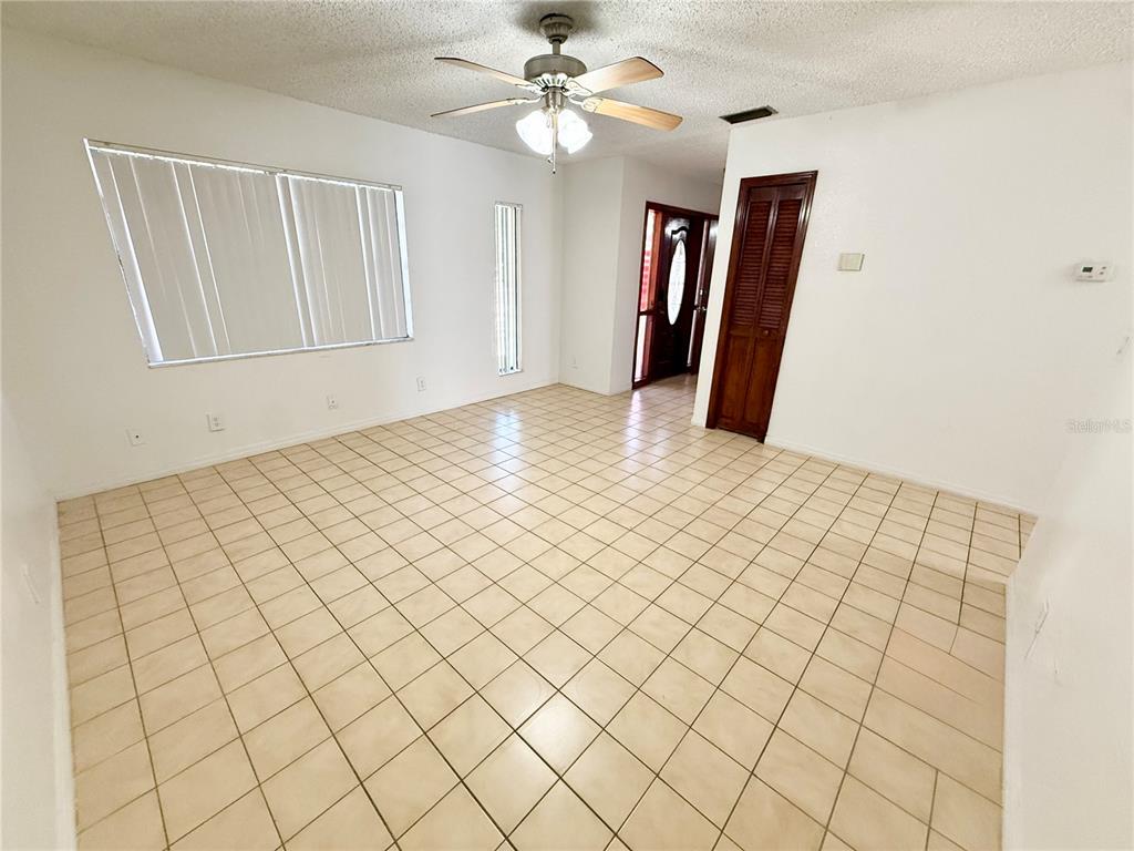 An empty room with beige tile flooring, a ceiling fan, and a dark wood door — 8336 JACKSON SPRINGS ROAD, TAMPA, FL