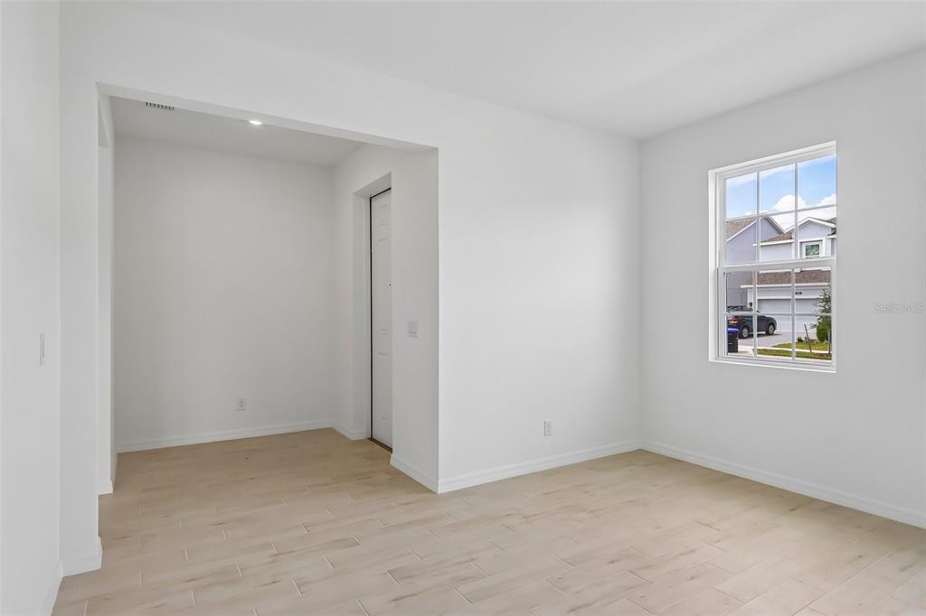 An empty room with light wood-look tile flooring, white walls, and a recessed alcove area — 2627 CAVANAUGH DRIVE, ORLANDO, FL
