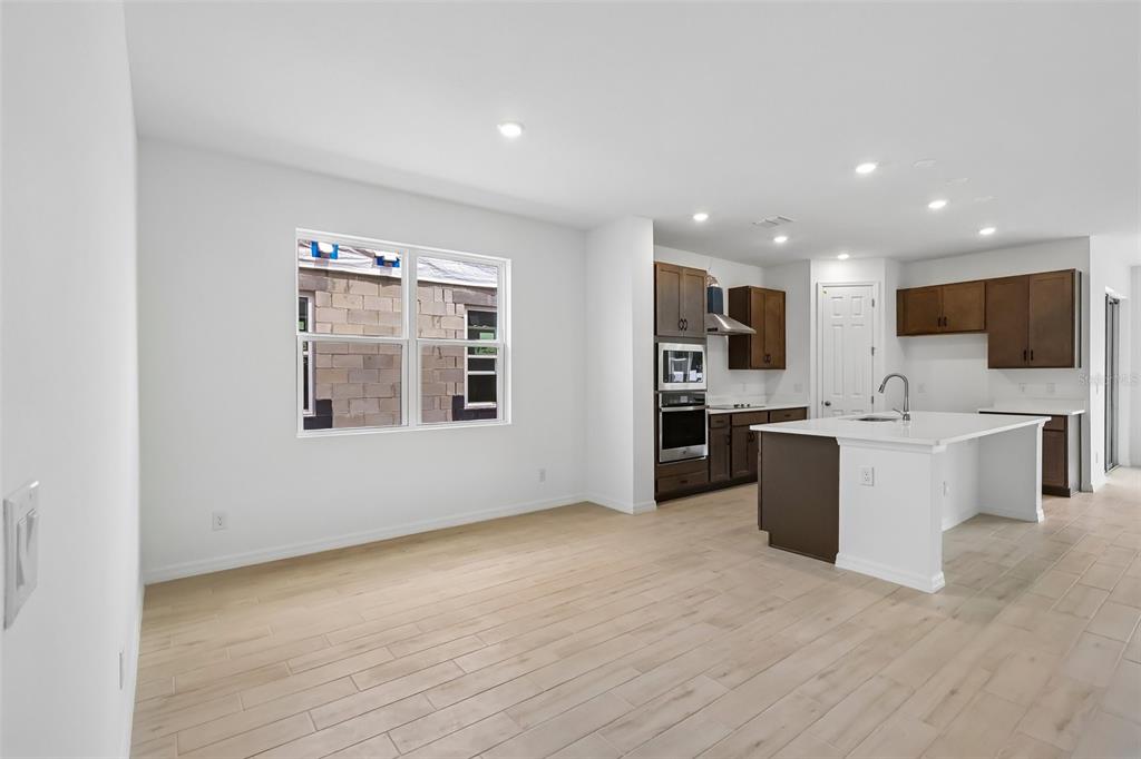 An open-concept kitchen and dining area featuring light wood-look tile flooring and white cabinetry — 2627 CAVANAUGH DRIVE, ORLANDO, FL