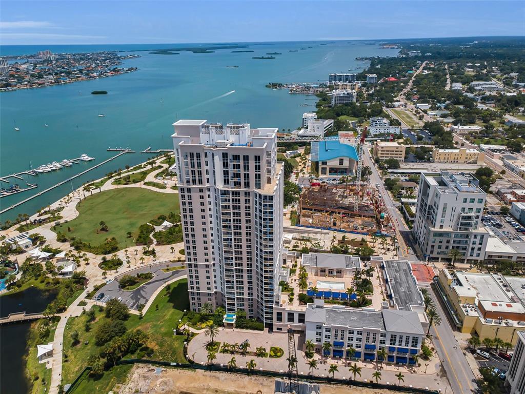 An aerial view shows a tall residential tower near a waterfront park and marina — 331 CLEVELAND STREET UNIT 1101, CLEARWATER, FL