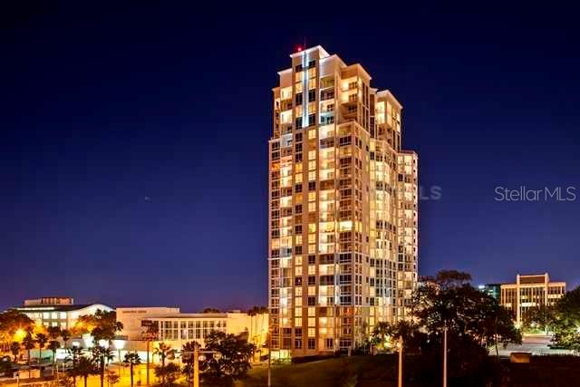 A tall, illuminated residential high-rise building stands against a dark night sky — 331 CLEVELAND STREET UNIT 1101, CLEARWATER, FL