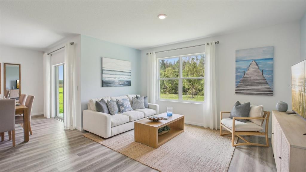 A living room with a white sofa, wooden coffee table, and a view of trees — 15018 CROSSHALL STREAM DRIVE, WIMAUMA, FL