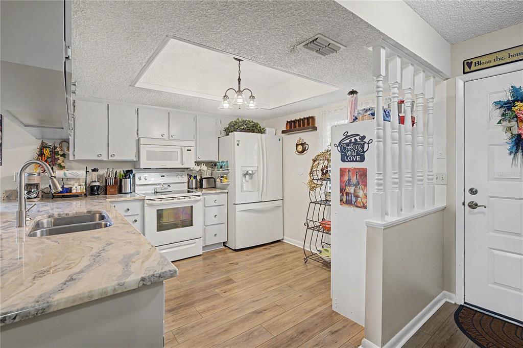 A kitchen with white cabinets, light countertops, wood-look flooring, and a white partition wall — 38225 BOXWOOD DRIVE, ZEPHYRHILLS, FL