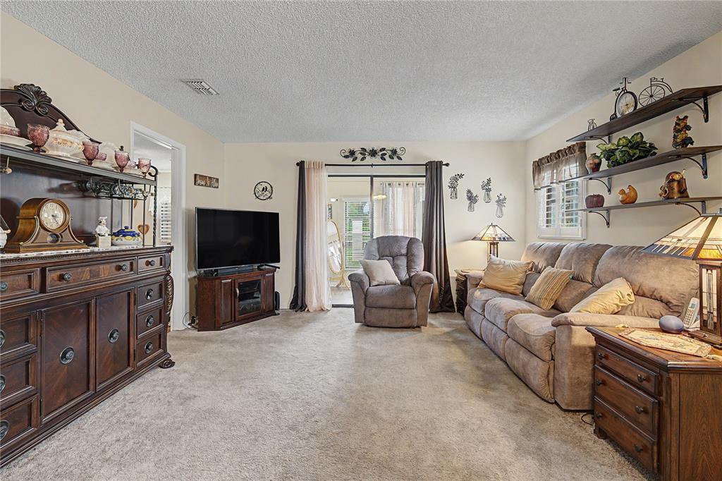 A living room features a brown sofa, a recliner, a large hutch, and wall shelving — 38225 BOXWOOD DRIVE, ZEPHYRHILLS, FL