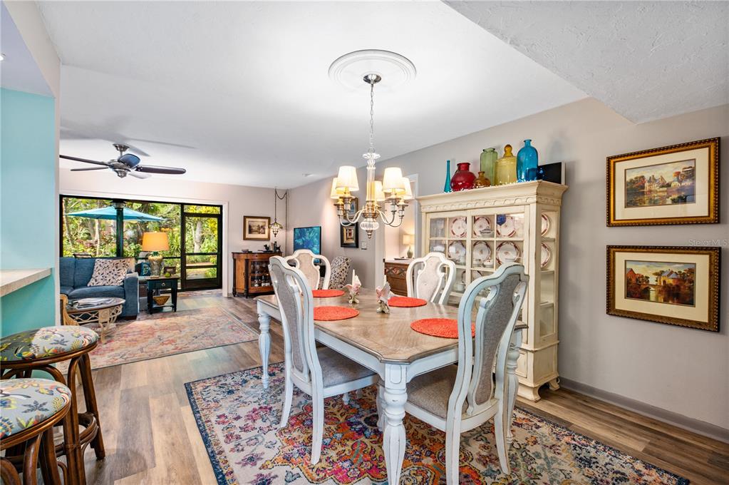 A dining room with a wooden table, white chairs, and a hutch sits near a living area — 1701 PELICAN COVE ROAD UNIT GL359, SARASOTA, FL